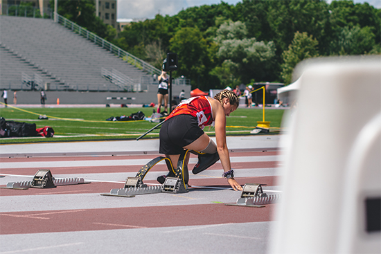Track athlete with running blades on her mark using a starting block ready to run
